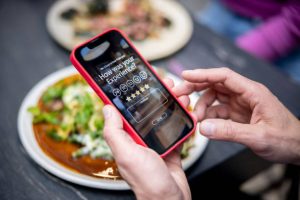 A customer with a smartphone leaving reviews about the restaurant he is in.